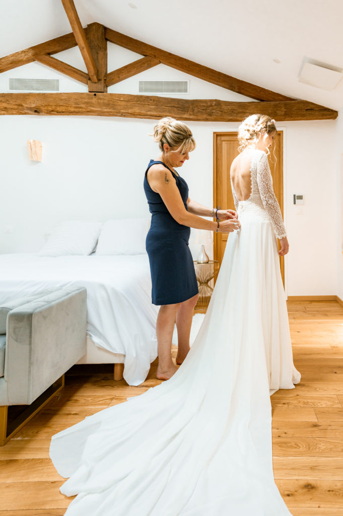 la maman qui attache la robe de la mariée